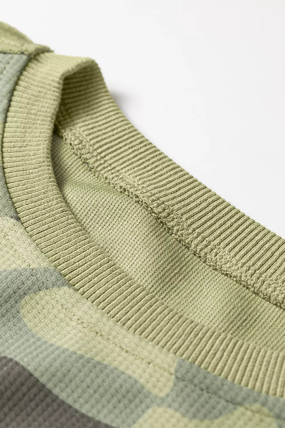 Neck view of the Say It In Camo Top in green camouflage with textured fabric, exposed seams, long sleeves, and side slits.