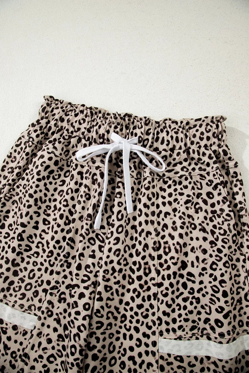 The Ziggy Pants in a beige and black leopard print with wide legs, a drawstring waist, and front patch pockets close up.