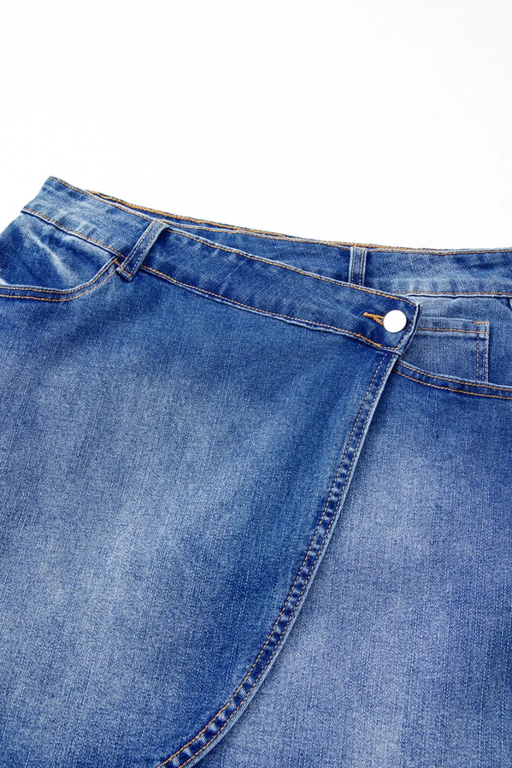 Shop The  Overlap Mini Skirt featuring a medium-blue wash, asymmetrical wrap-style front, curved seam detailing, and flattering A-line fit.