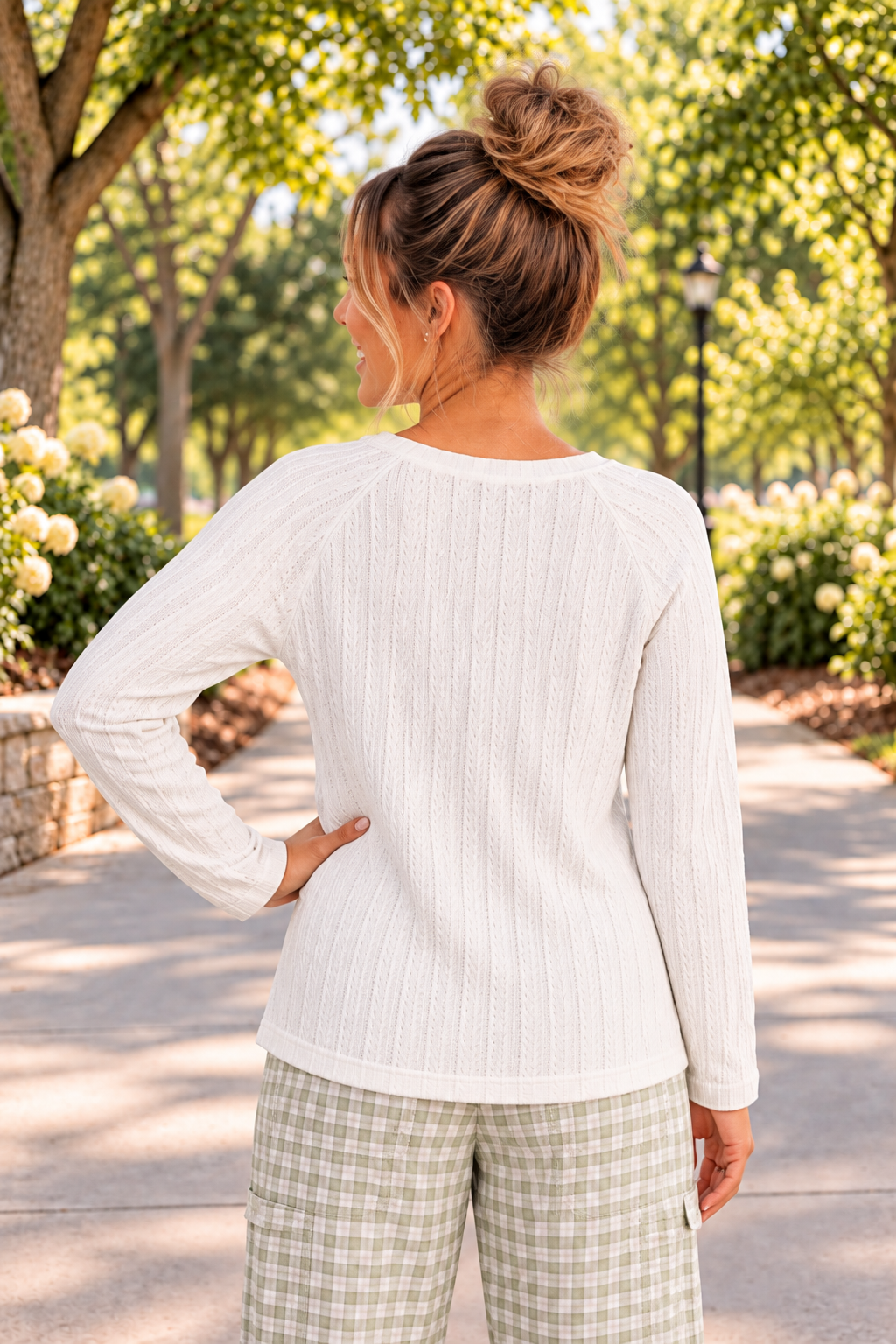Woman is wearing a white raglan style long sleeve top with a round neck. It is ribbed, textured knit and slightly stretchy. Front view.