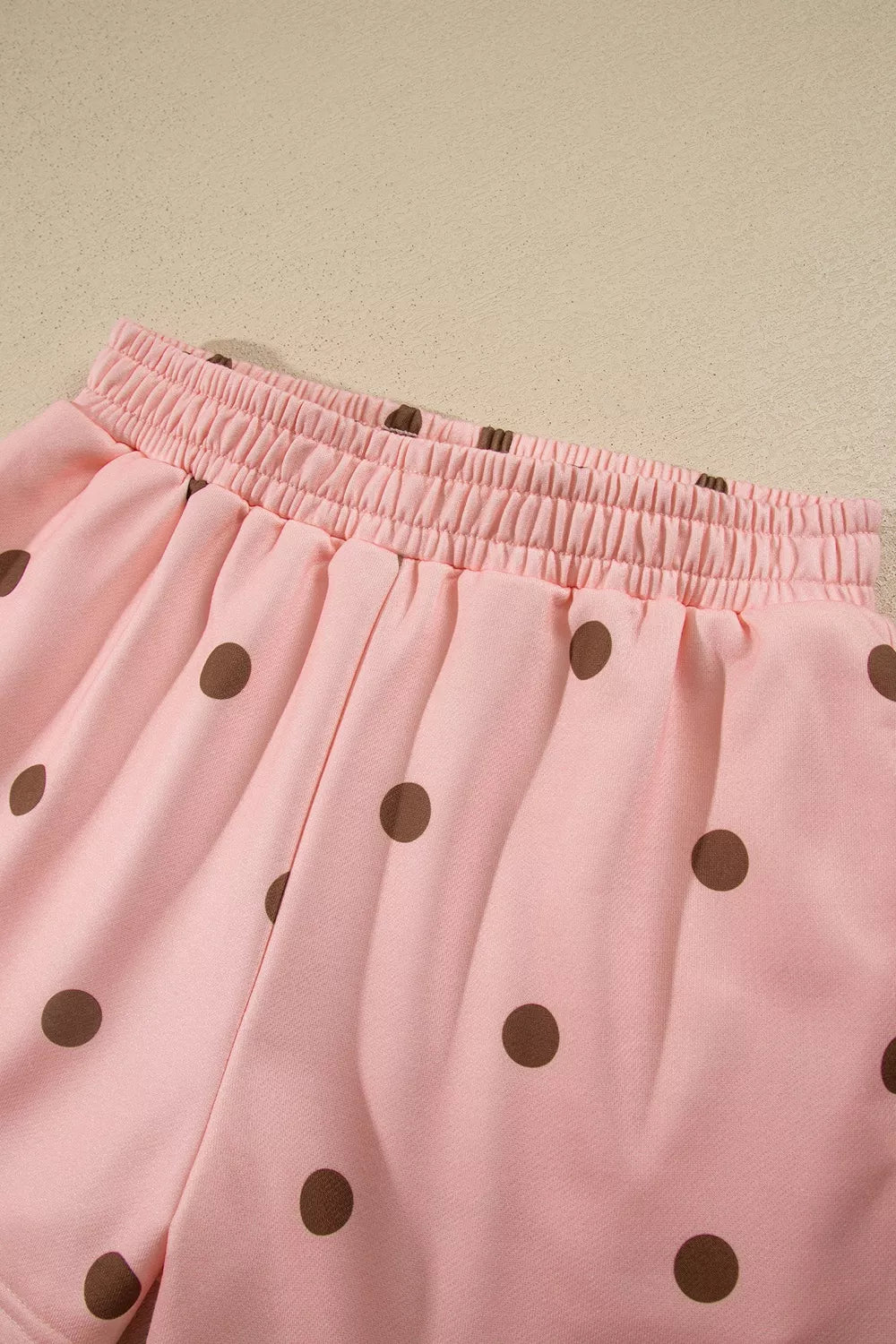 Sweet Pea Short Set in pink with brown polka dots, featuring a long-sleeve top, white mock neck and cuffs, and matching shorts.