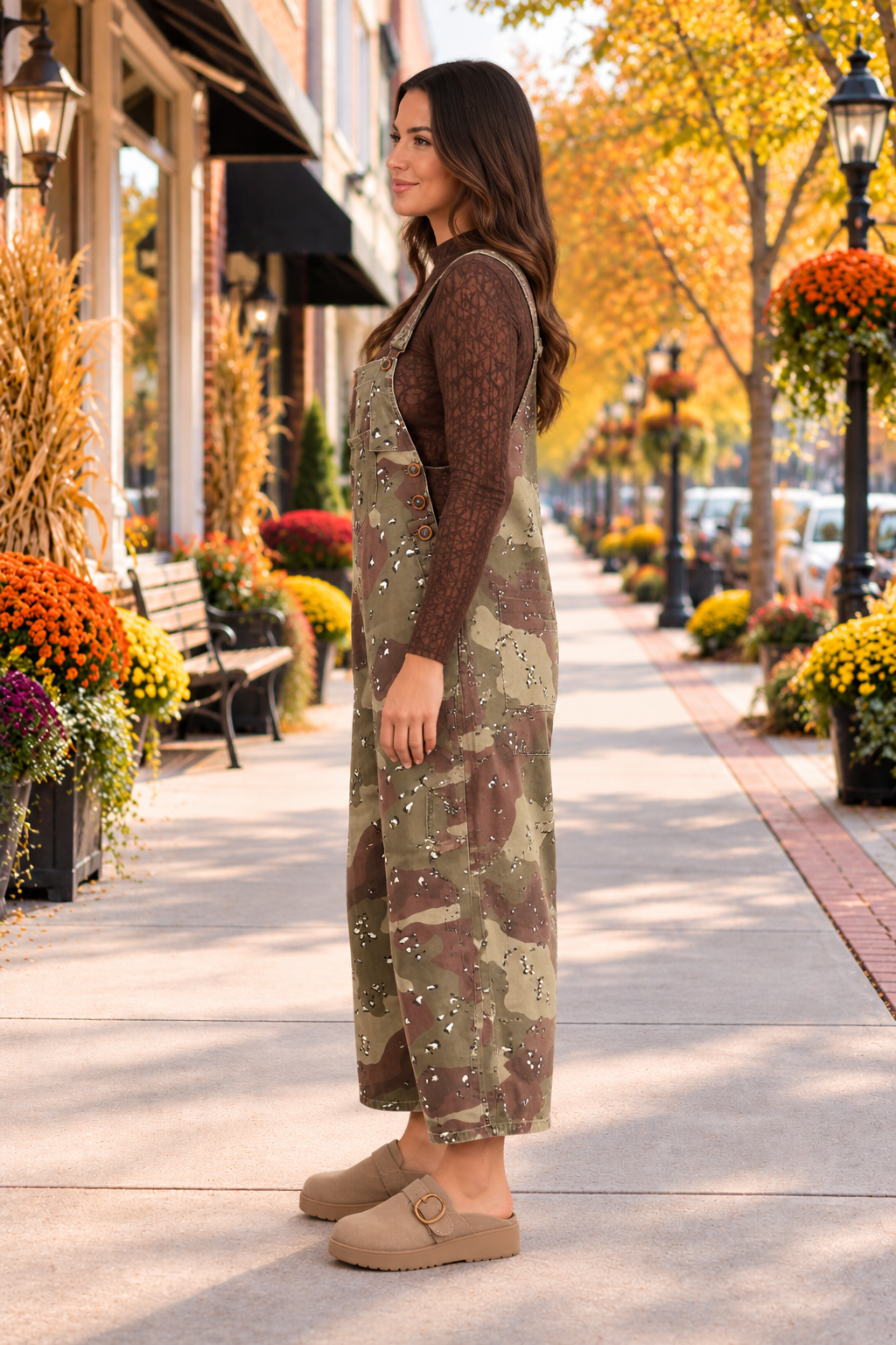 Side view of the Blending In Overalls in green and brown camouflage with adjustable straps, bib pocket, side buttons, and cropped wide legs.