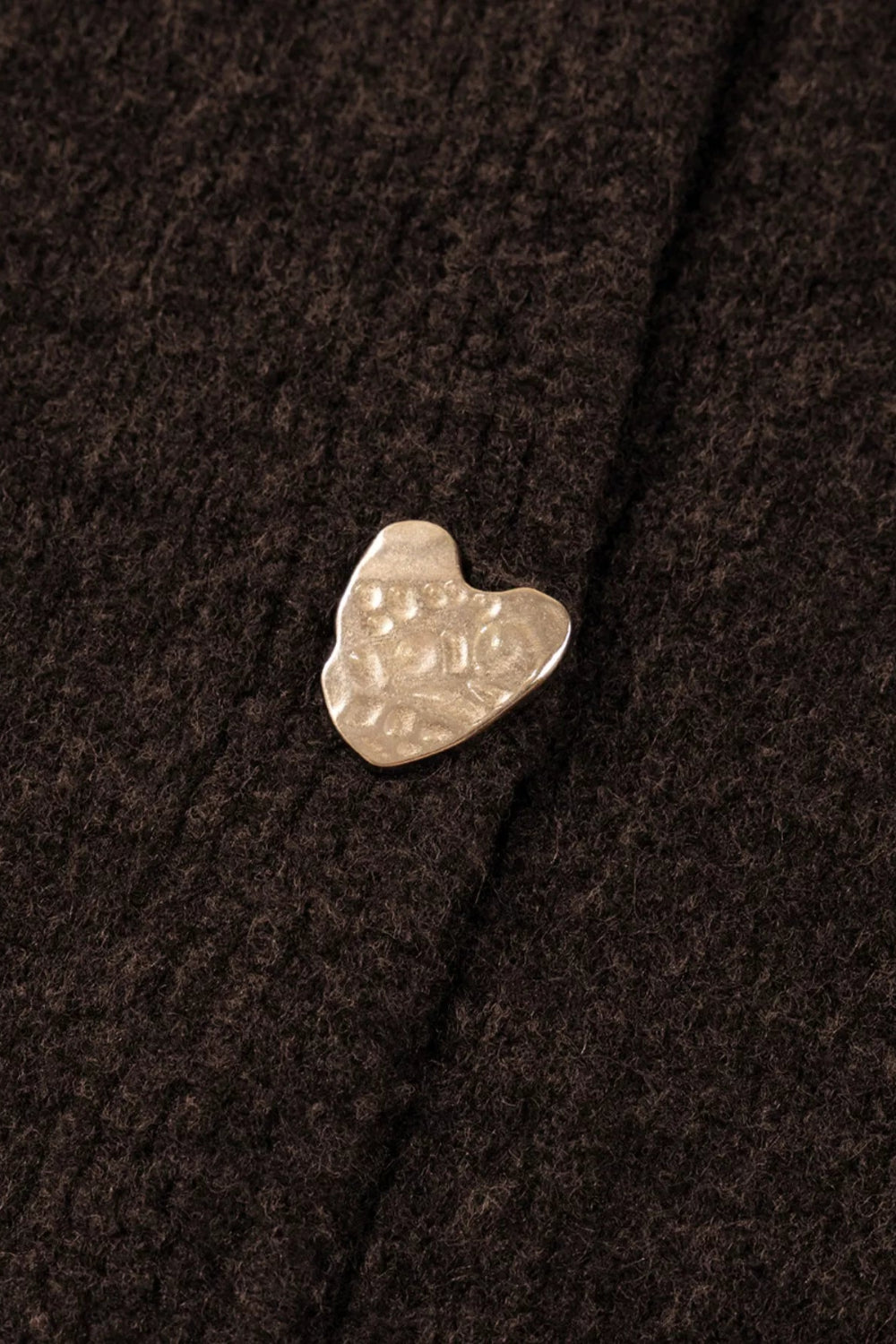 cardigan, chocolate color, long sleeve, v-neck, metal heart shaped button on front and cuffs, ribbed, medium length, slightly stretchy, close up button view