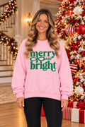 Shop the Merry And Bright Graphic Sweatshirt in vibrant pink with green lettering. Perfect for casual winter outfits.