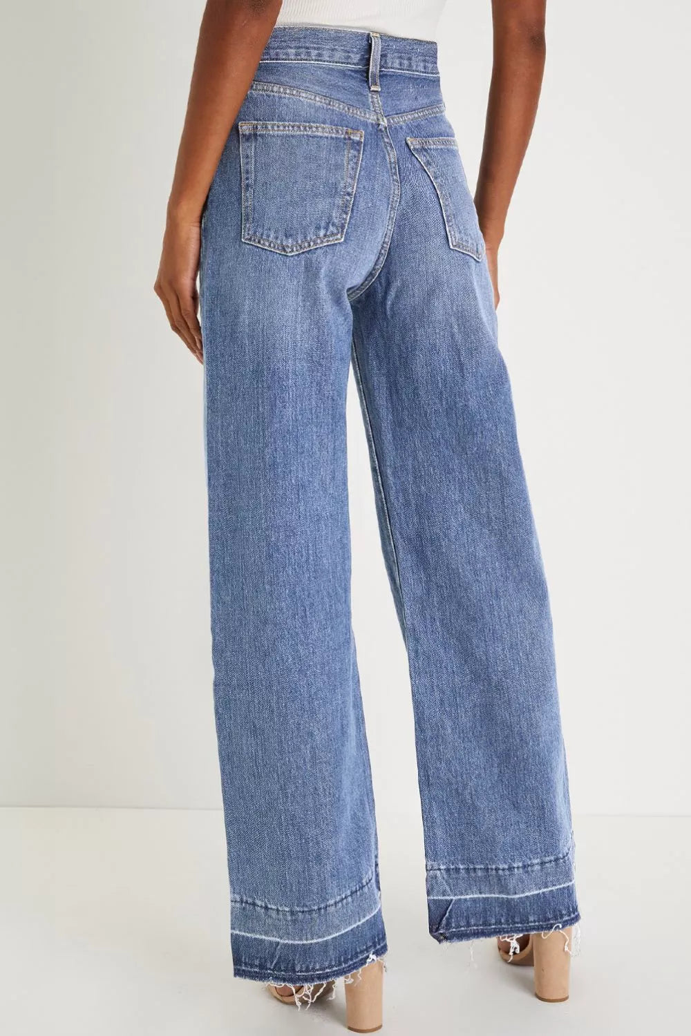 Jeans, high waist, wide leg, belt looped, pocketed, button/zipper closure, light wash, release hem, frayed hem, slightly stretchy, back view