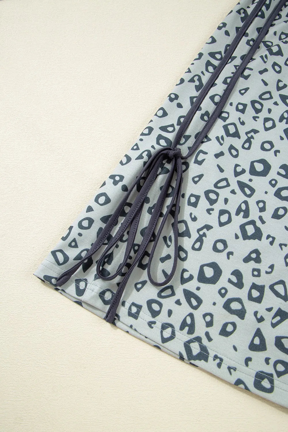 Pants, leopard print, high waist, elastic waistband, no drawstring, piping, side ties, pocketed, gray in color, some stretch close up view