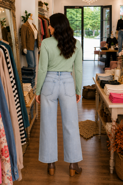 Model is shown wearing the back view of distressed, striped, light wash, wide leg jeans with button fly closure. Jeans have belt loops are pocketed with no stretch.