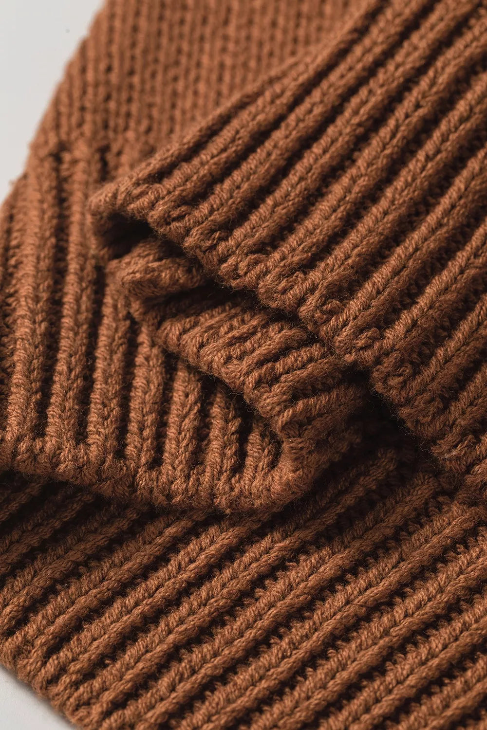 Close up hem view of the Horseshoe Sweater in rust brown knit with a white horseshoe graphic, crew neckline, and ribbed cap sleeves.