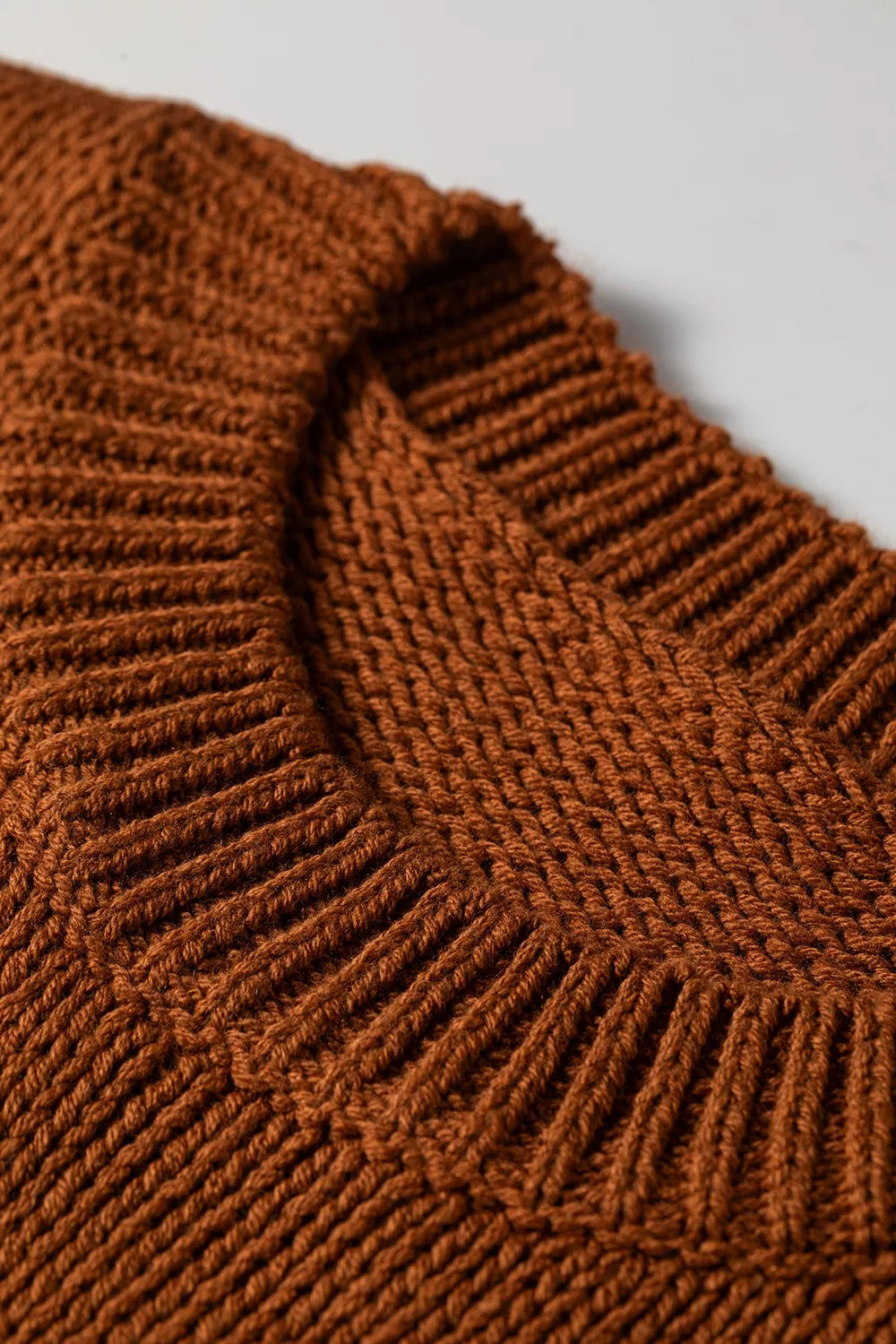 Close up neck view of the Horseshoe Sweater in rust brown knit with a white horseshoe graphic, crew neckline, and ribbed cap sleeves.