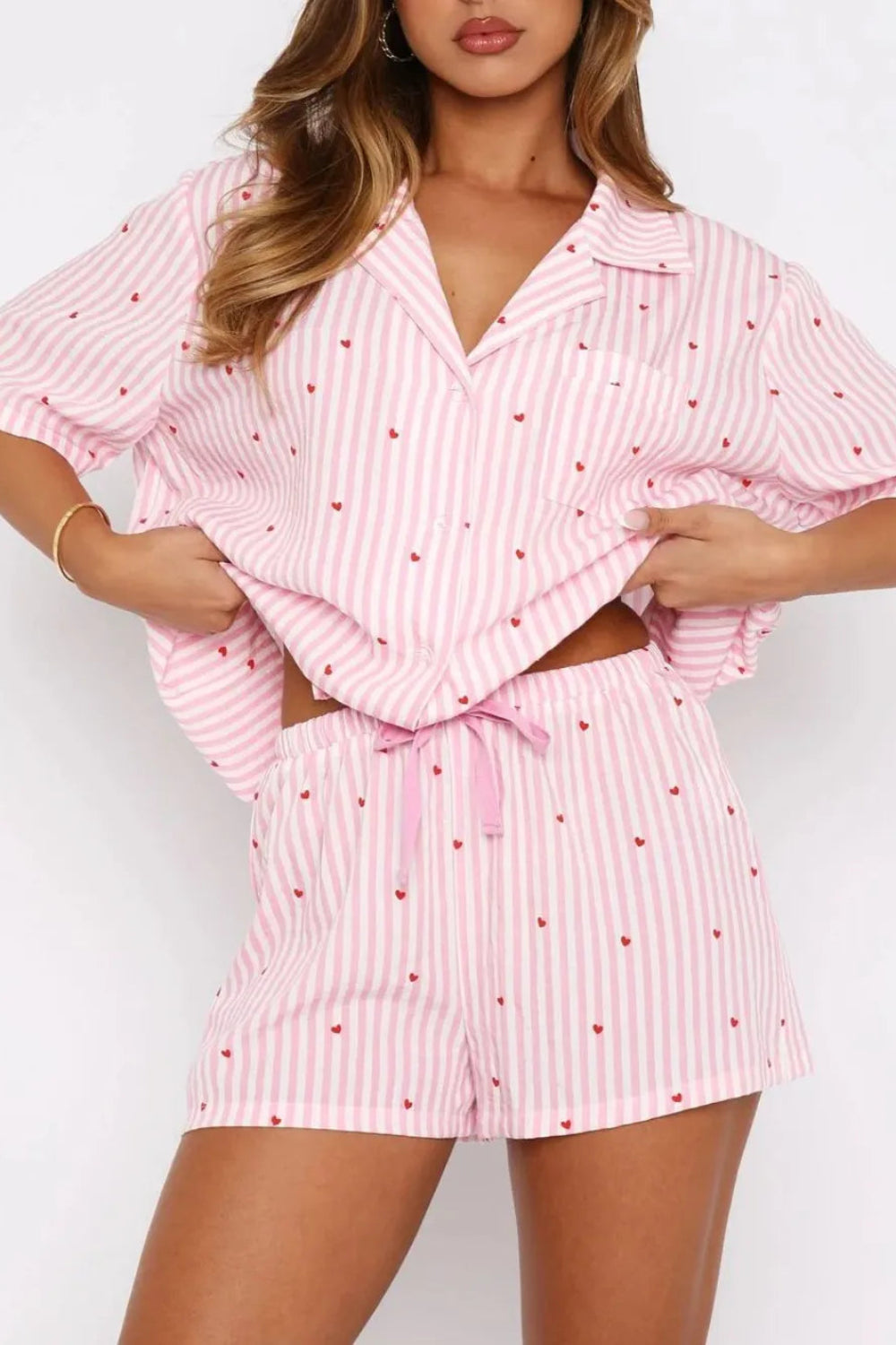 two-piece pajama set, striped with hearts, collared neck, short sleeve, front pocket, button down, shorts, elastic waist, bow tie, some stretch, front close up