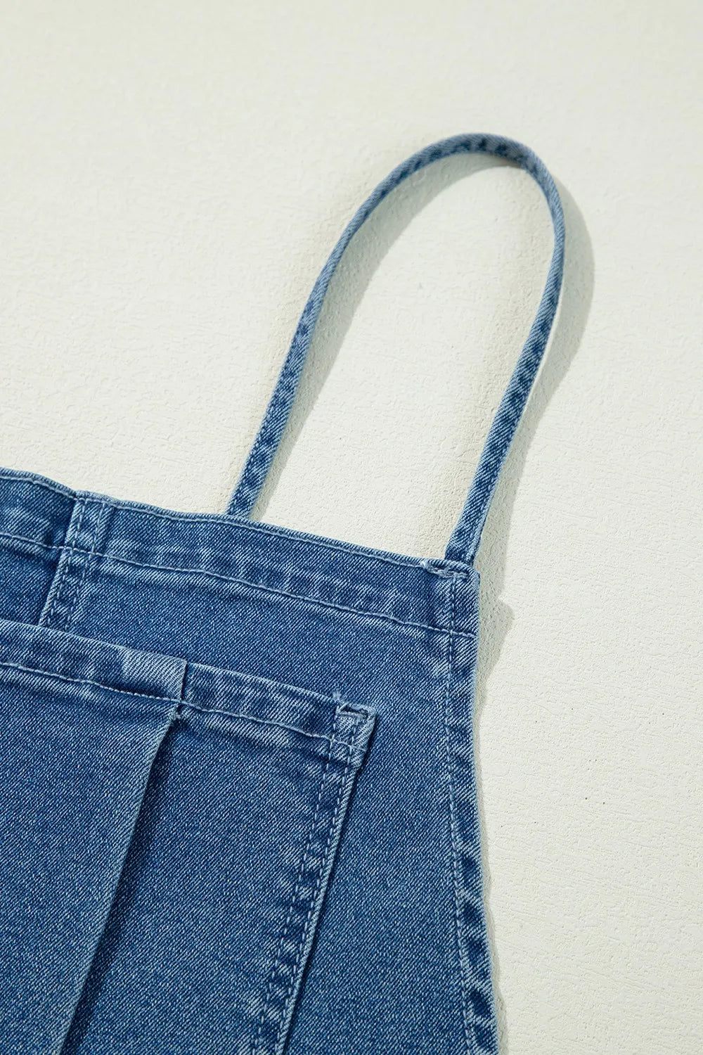 Denim overalls, adjustable tie straps, square neck, backless, wide leg, pocketed, button sides, no stretch close up view