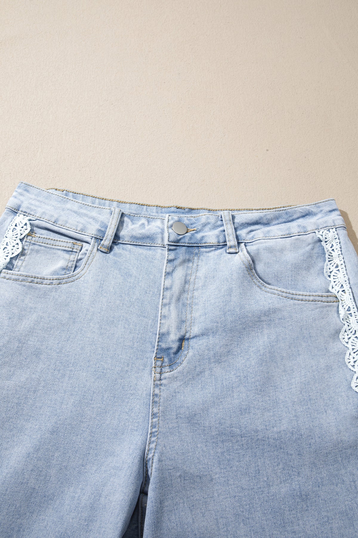 The Second Look Jeans in a light wash with wide cuffed legs, double white lace side panels, and back pockets, shown close up.
