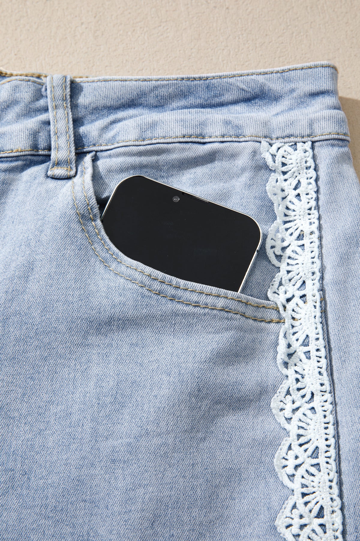 The Second Look Jeans in a light wash with wide cuffed legs, double white lace side panels, and back pockets, shown close up.
