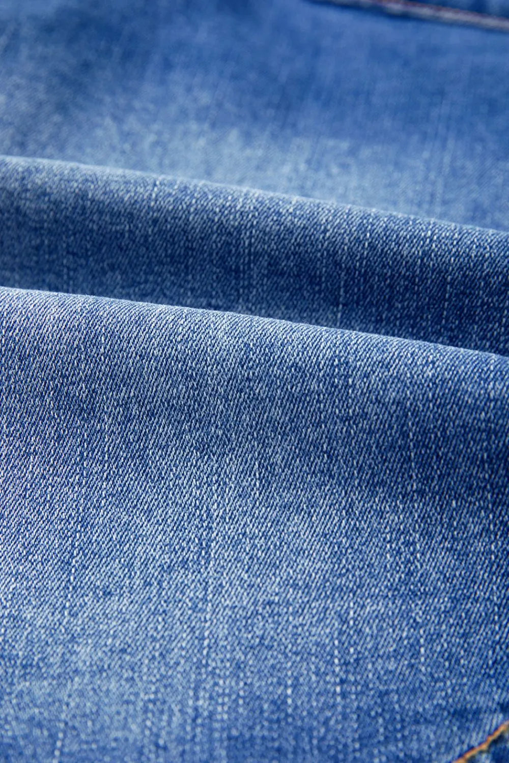 Shop The  Overlap Mini Skirt featuring a medium-blue wash, asymmetrical wrap-style front, curved seam detailing, and flattering A-line fit.