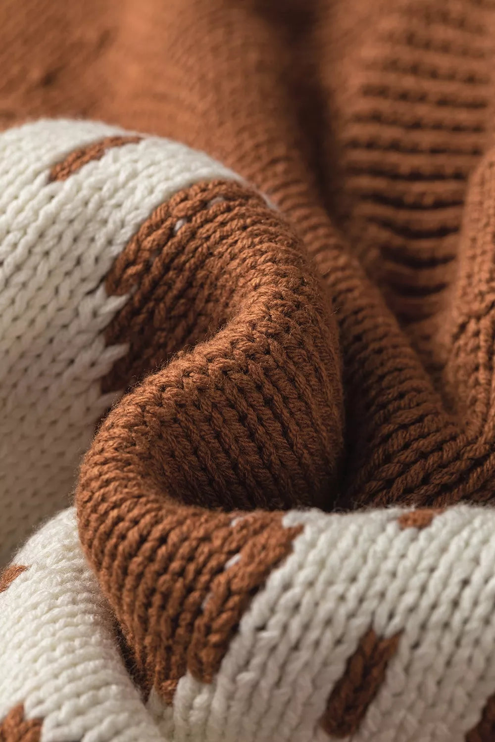 Close up knit view of the Horseshoe Sweater in rust brown knit with a white horseshoe graphic, crew neckline, and ribbed cap sleeves.