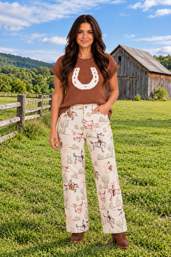 Front view close up of the Rodeo Revival Jeans in cream with a cowboy, horse, and cactus print, high waist, and wide legs.