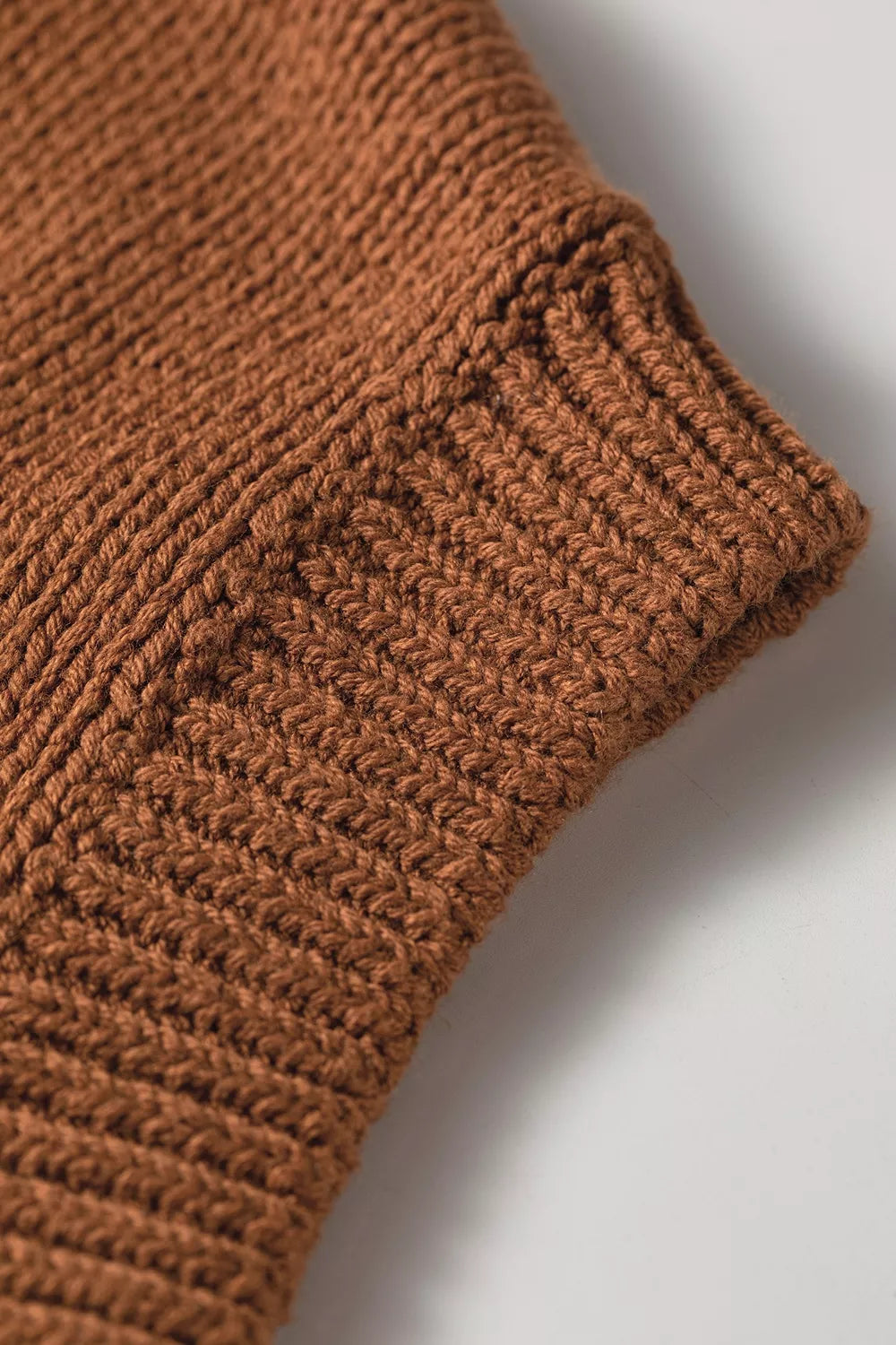 Close up sleeve view of the Horseshoe Sweater in rust brown knit with a white horseshoe graphic, crew neckline, and ribbed cap sleeves.