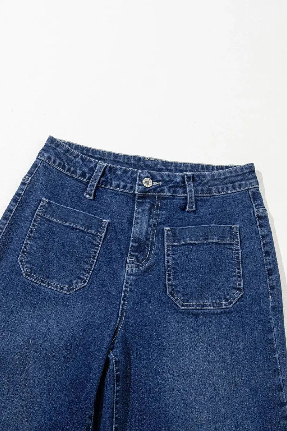 Jeans, high-waist, wide leg, front patch pockets, v-shaped back pockets, wide cuffs, vintage medium wash, button/zipper closure, belt loops, slightly stretchy, front view close up