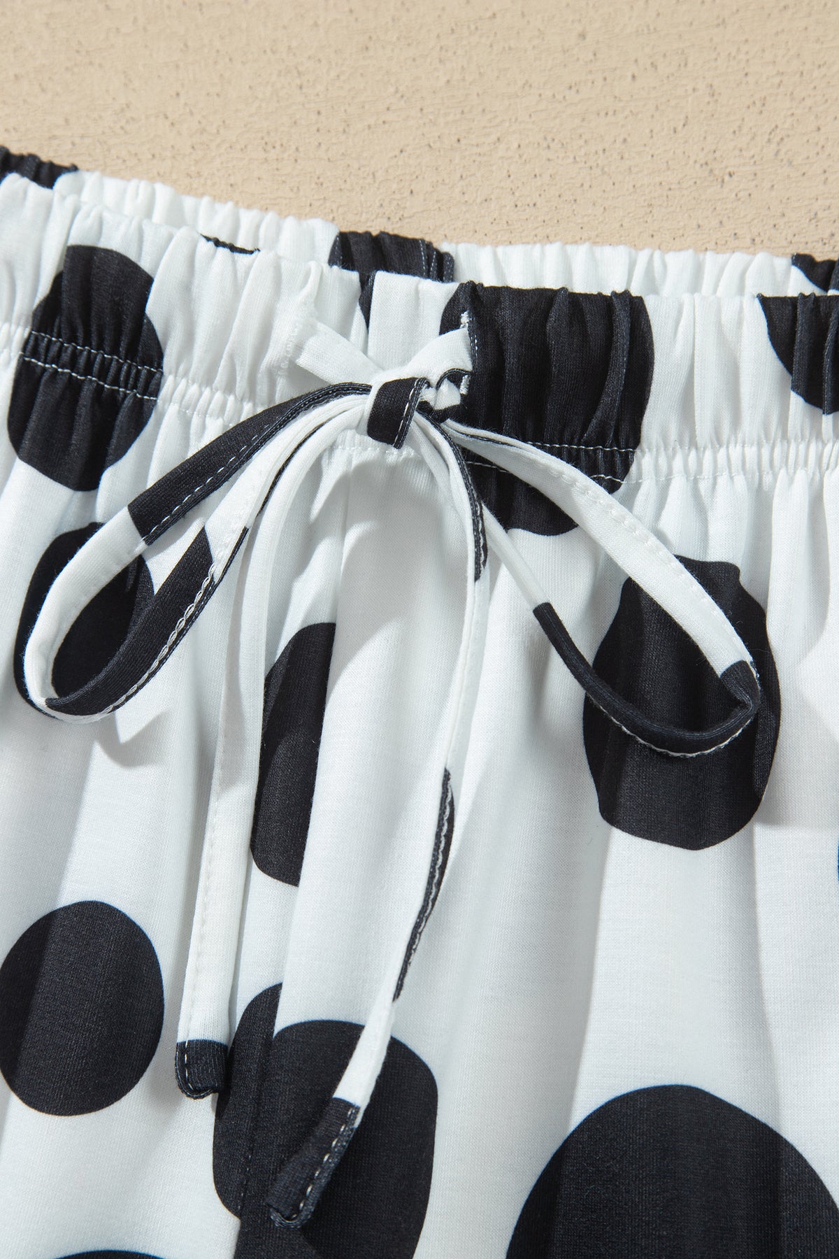 Point Taken Pant Set In Black with an ivory-and-black polka-dot sweatshirt and matching wide-leg drawstring pants close up view.