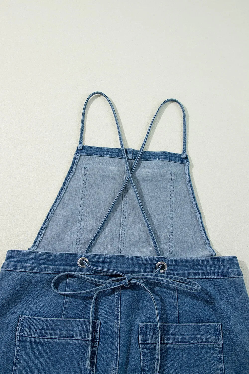 Denim overalls, adjustable tie straps, square neck, backless, wide leg, pocketed, button sides, no stretch close up view