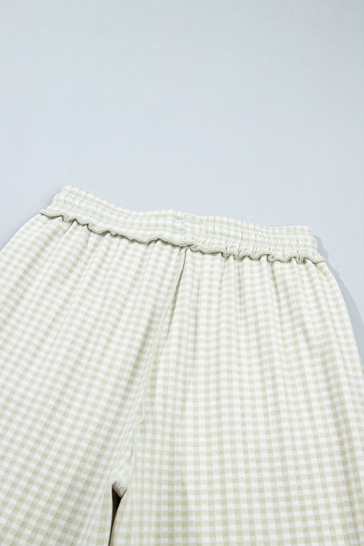 The Reece Pants in light green and cream gingham with wide cuffed legs, a drawstring waist, front pockets, and vertical seams back view close up of waist.