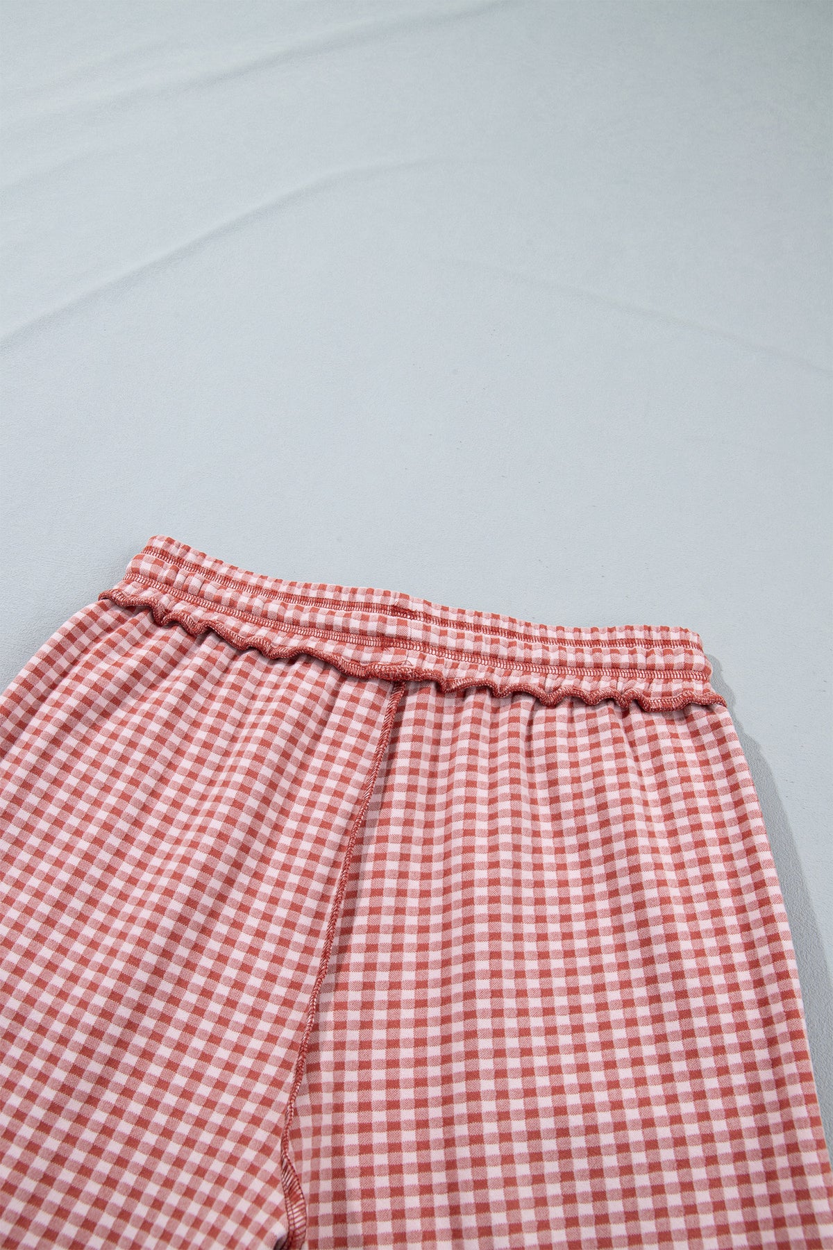 The Reece Pants in red and cream gingham with wide cuffed legs, a drawstring waist, front pockets, and vertical seams close up back waist view.