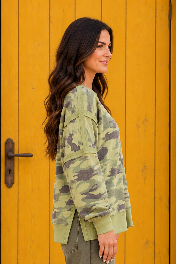 Side view of the Say It In Camo Top in green waffle knit with a camouflage print, exposed seams, long sleeves, and front hem slits.