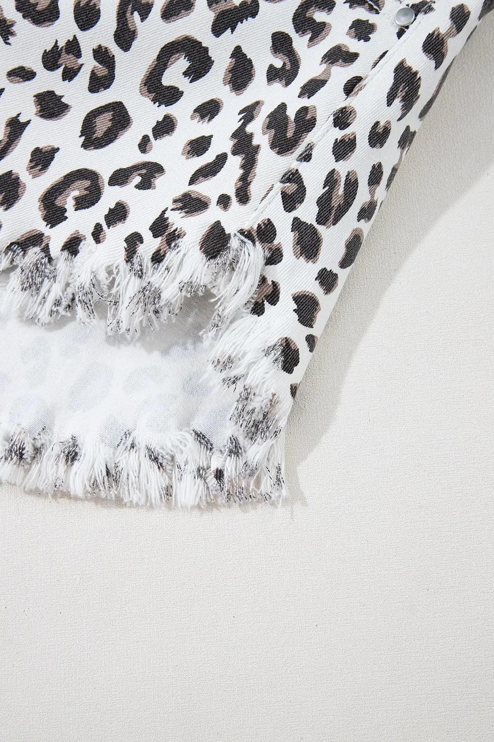 Denim shorts, Leopard print, White, Frayed hem, High waist, Functioning pockets, Belt loops, Zipper and button closure, Medium-high elasticity Close up view