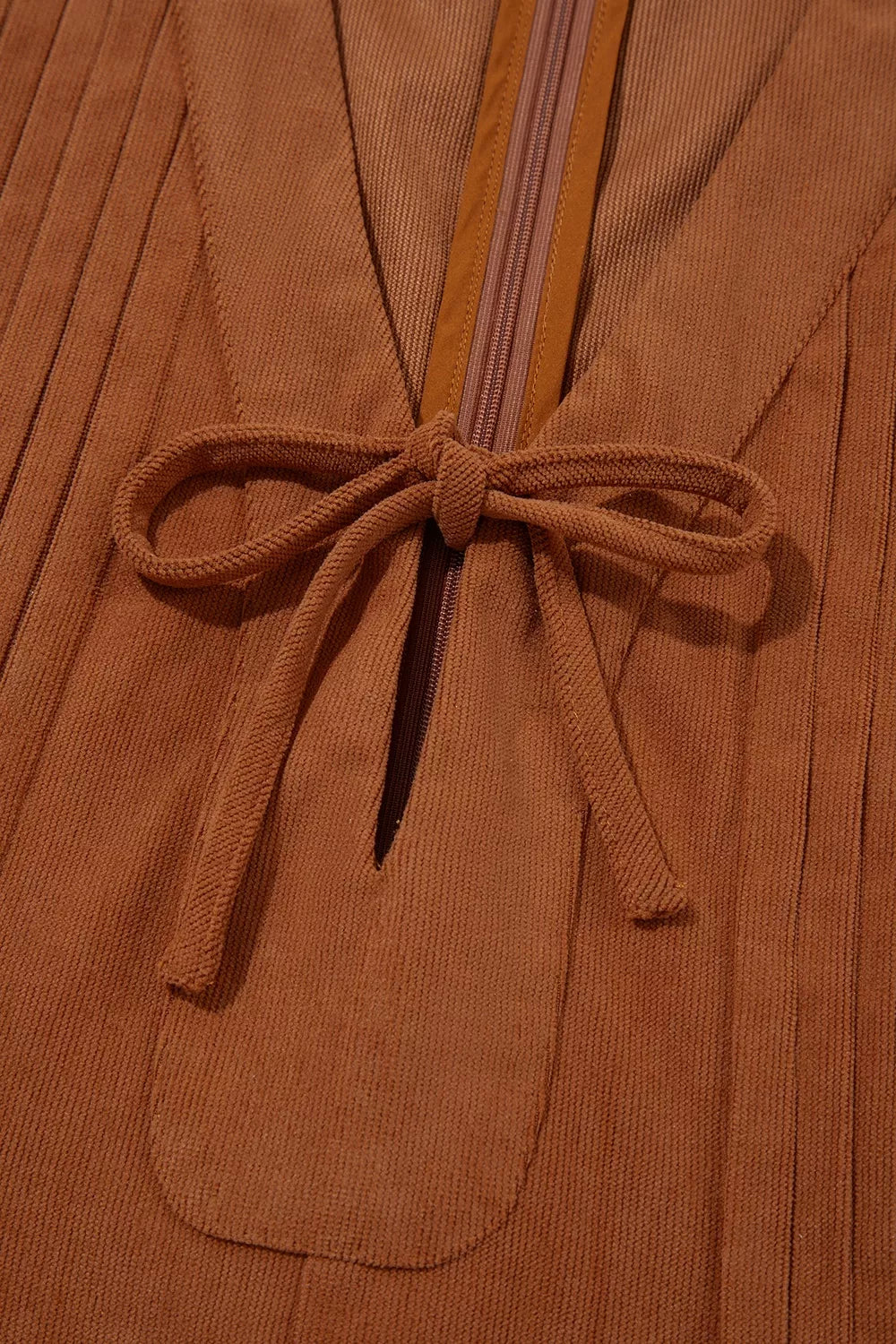 Front view of the As You Were Romper in rust brown corduroy with a tie V-neck, back zipper, pleated details, and side pockets.