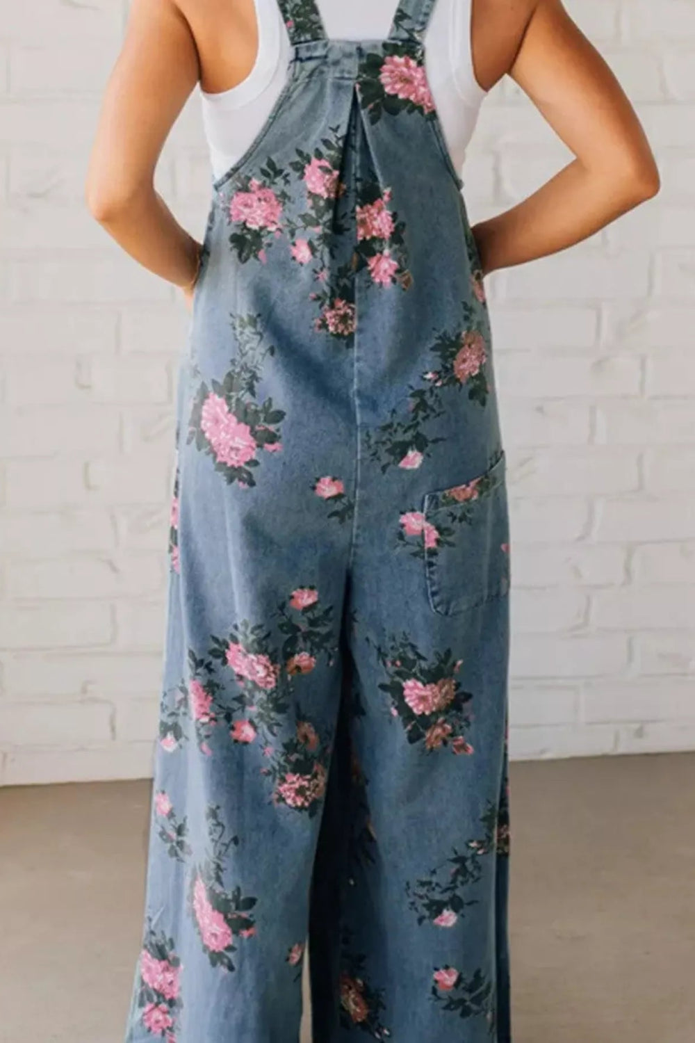 Overalls, floral print, wide leg, front bib pocket, front pockets, pleated, button straps, single back pocket, side button closure sit high, medium wash, slightly stretchy, back view close up
