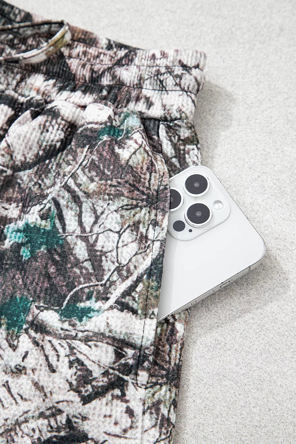 The Renegade Short Set in woodland camouflage with a long-sleeve button-front top and drawstring shorts with pockets close up view.