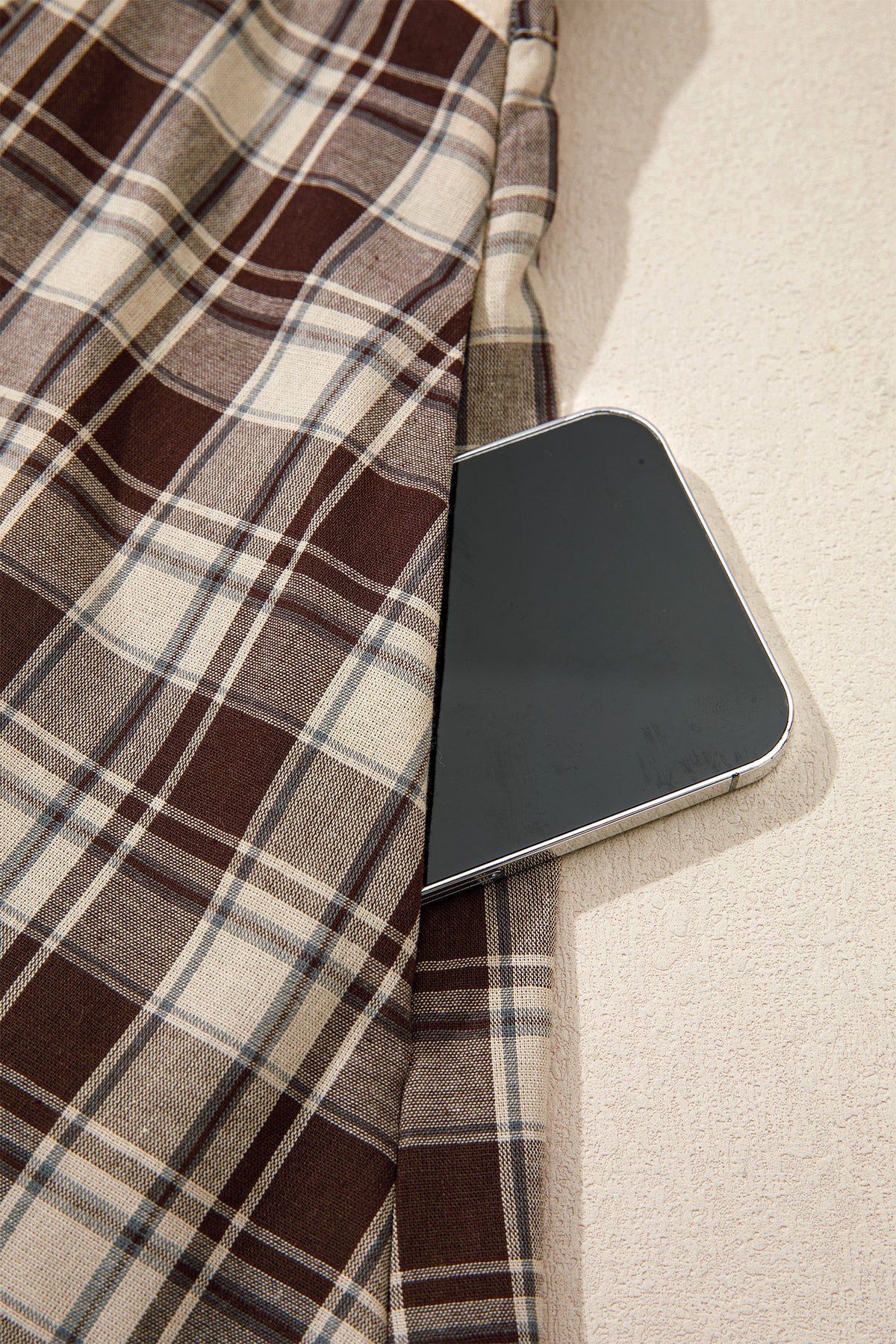 Pocket view of the Well Thought Of Mini Dress in brown and cream plaid with a collared button front, long sleeves, and pockets.